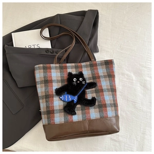 Detail of checkered tote bag with a cute plush cat patch and brown leatherette trim