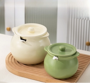 Detailed view of ceramic lard jars with lids and spoons on a textured wooden tray