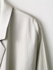 Vista dettagliata del tessuto beige del blazer con trama intrecciata e cuciture fini