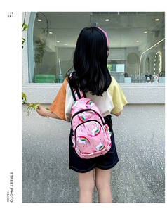 Vista detallada de la espalda de una mochila rosa infantil con estampados de unicornio y arcoíris
