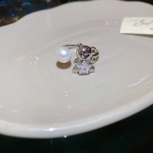 Macro shot of a silver ring with a white pearl and a teddy bear holding a star