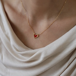 Elegant gold titanium necklace with a red heart pendant worn on model's neck