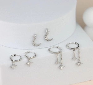 Detailed close-up of three silver star and moon earrings with cubic zirconia inlay