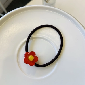 Élastique à cheveux fleur en gelée rouge et jaune avec cordon noir sur assiette blanche