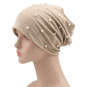 Détail du bonnet beige orné de perles artificielles blanches et de strass brillants