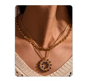 Detail einer zweilagigen Goldkette mit Schlangenkette und blauem Strass-Anhänger