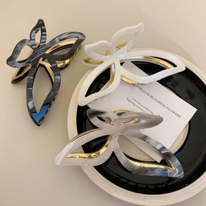 Three elegant butterfly hair claws in marble and white acetate with gold metal springs