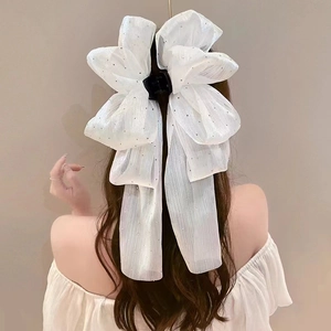 Detail of white mesh bow hair claw clip with silver glitter and long ribbons for women