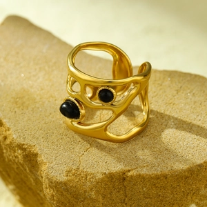 Detailed shot of golden hollow ring with black stones on a textured natural rock