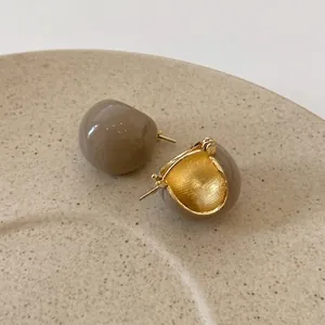 Vue macro de boucles d'oreilles en émail thé au lait avec finition dorée sur plateau
