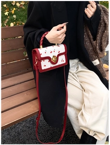 Detail of cherry print bag with golden flower clasp and red twisted handle