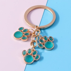 Close-up of golden metal cat paw charms with teal enamel on a colorful background