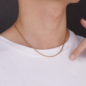 Close-up of golden stainless steel corn chain necklace on a model wearing white t-shirt