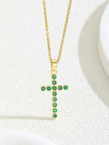 Macro detail of gold-plated cross pendant featuring 11 sparkling emerald green zircons