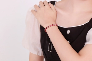 Detailed view of beaded adjustable bracelet with red gradient beads on a woman's wrist
