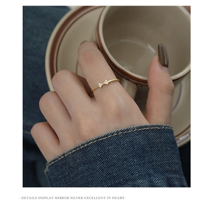 Close-up of golden bow-shaped silver ring with sparkling zircons worn by a model