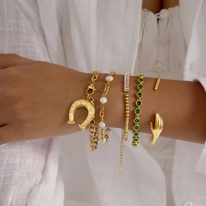 Golden horseshoe and tennis bracelet set with crystals and pearls worn together