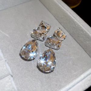 Macro shot of silver drop earrings with faceted crystals resting in a velvet box