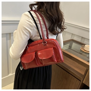 Dettaglio della borsa rossa con due tasche frontali e finitura lucida su una modella