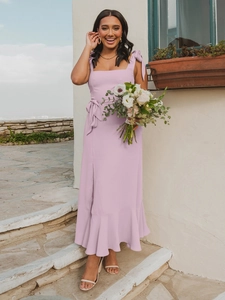 Detail view of pink midi dress featuring shoulder bow ties and a ruffled hemline
