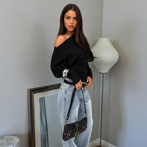Modern black off-shoulder long sleeve top paired with blue jeans and a gold buckle handbag
