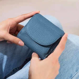 Mini portafoglio blu in pelle fiore con protezione RFID tenuto su uno sfondo di jeans blu