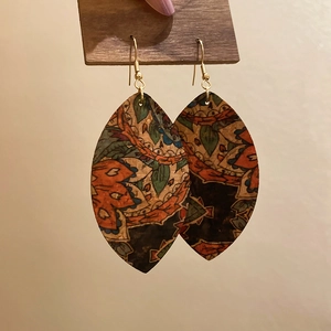 Detail of leaf-shaped bohemian earrings with vintage floral patterns and metal hooks