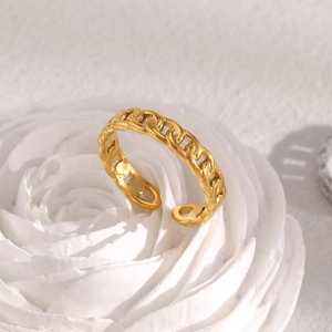 Detailed macro of 18K gold plated stainless steel curb chain ring on a white plaster base