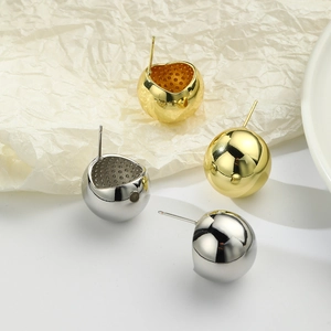Polished gold and silver geometric sphere stud earrings displayed on a minimalist background