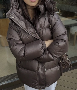 Detail of glossy brown padded jacket showing fabric texture and drawstring hood