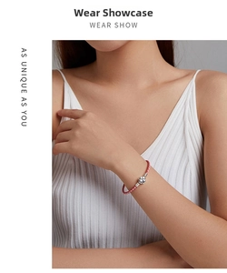 Pink braided leather bracelet on wrist featuring a silver four-leaf clover charm