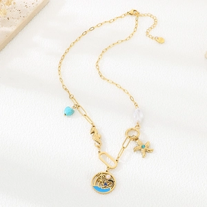 Detailed close-up of stainless steel starfish, seahorse and pearl charms on golden necklace