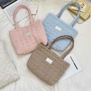 Three quilted gingham tote bags in pink, blue, and brown shown in a cozy flat lay scene