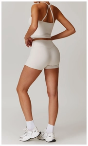 Vista posteriore di completino sportivo bianco crema con pantaloncini a vita alta