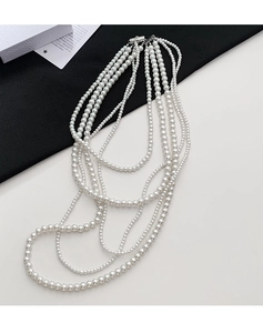 Detailed view of multilayer glass pearl necklace with silver clasp on a chic backdrop