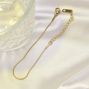 Detail of rose gold snake chain anklet with lobster clasp on elegant white silk