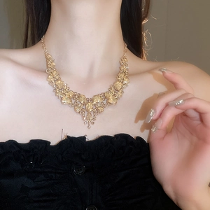 Close-up of model wearing gold necklace set with amber rhinestones and teardrop design