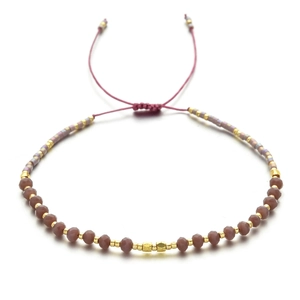 Nahaufnahme eines handgefertigten Boho-Armbands mit violetten Kristallen und Zugband