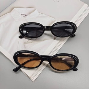 Detail of oval retro sunglasses in black and tea lenses on white shirt backdrop