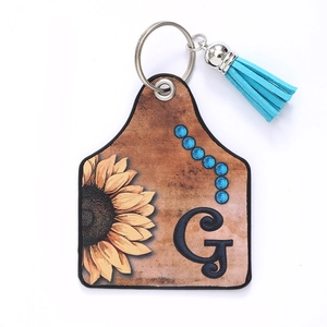 Detail of western leather sunflower keychain with blue fringe tassel and letter G