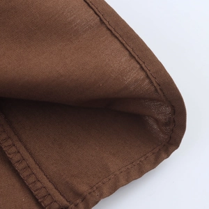 Detailed close-up showing double-needle stitching and hem on the brown linen dress fabric
