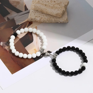 Close-up of magnetic heart clasp connecting black and white beaded couple bracelets