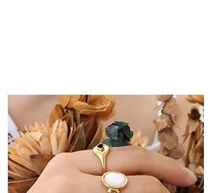 Detail of hand wearing gold heart and oval signet rings with black and white inlay