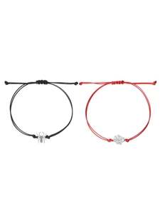 Detail of couple bracelets featuring black spider and red cobweb charms on woven ropes