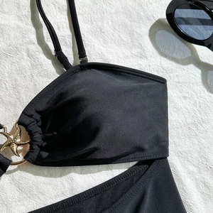 Gedetailleerde close-up van de gouden zeester metalen gesp op een zwarte bikini