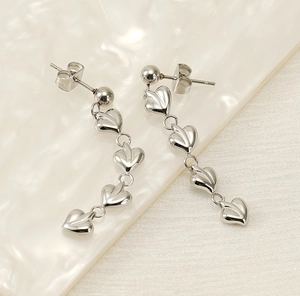 Détail de boucles d'oreilles pendantes cœurs argentés avec surface polie et fermoir papillon