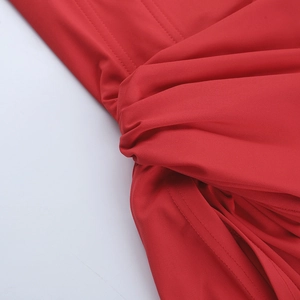 Détail de la robe de soirée rouge montrant le nœud froncé à la taille et la texture