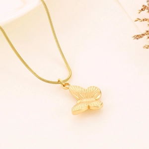 Macro detail of golden butterfly pendant with textured finish on a sleek snake chain
