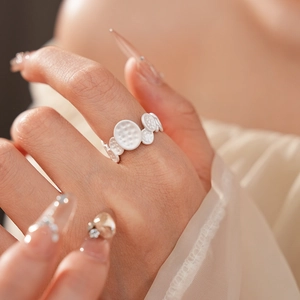 Macro shot of minimalist white enamel oval textured open ring on model's index finger