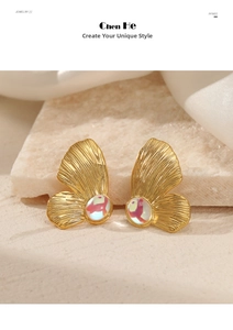 Detail view of butterfly gold earrings with iridescent opal stones on textured stone surface